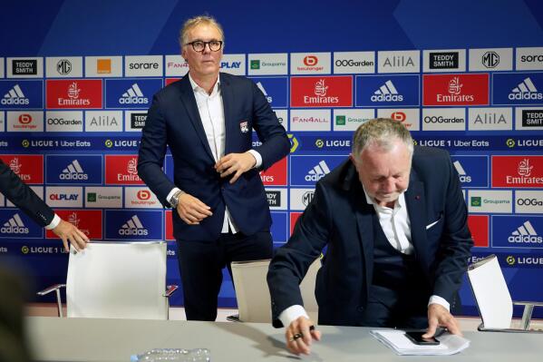 Lyon's new coach Laurent Blanc, left, prepares to pose for photographers during a press conference to announce his appointment, in Decines, near Lyon, central France, Monday, Oct. 10, 2022. Blanc signed a two-year contract to replace Peter Bosz who was fired after only a few months in charge. (AP Photo/Laurent Cipriani)