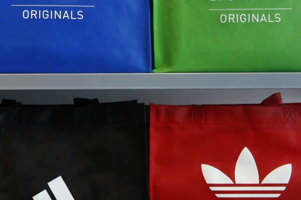 FILE - In this file photo dated May 7, 2009 the company's logo is pictured on shopping bags in the Adidas outlet store in Herzogenaurach, southern Germany. Adidas has launched an investigation into allegations of “compliance violations” in China after receiving an anonymous letter earlier this month accusing local executives of embezzling millions of euros, according to news media reports. (AP Photo/Matthias Schrader, File)