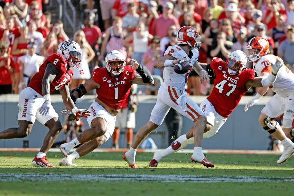 Clemson quarterback Cade Klubnik (2) passes the ball as North Carolina State linebacker Jaylon Scott (2), defensive tackle Davin Vann (1), and defensive lineman Red Hibbler (47) close in during the first half of an NCAA college football game in Raleigh, N.C., Saturday, Oct. 28, 2023. (AP Photo/Karl B DeBlaker)