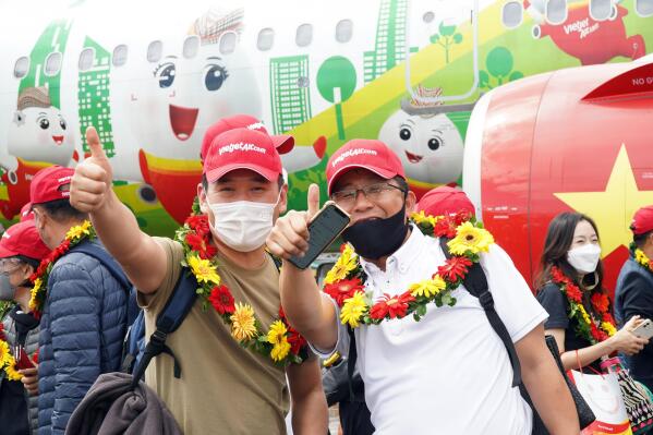 Tourists pose for a photo after landing on Phu Quoc island, in Vietnam, Saturday, Nov. 20, 2020. More than 200 foreign tourists arrived on Vietnam's largest Phu Quoc island on Saturday, being the first to visit the Southeast Asian country after nearly two years of border closure due to COVID-19. (VietjetAir via AP)