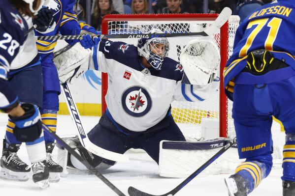 Winnipeg Jets goaltender Connor Hellebuyck (37) makes a save in traffic during the first period of an NHL hockey game against the Buffalo Sabres, Thursday, Jan. 12, 2023, in Buffalo, N.Y. (AP Photo/Jeffrey T. Barnes)