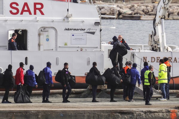 Migrants board an Italian Coast Guard vessel as part of a transfer operation from the asylum processing centers in Albania back to Italy following a court decision in Rome, at the port of Shengjin, northwestern Albania, Saturday, Feb. 1, 2025. (AP Photo/Vlasov Sulaj)