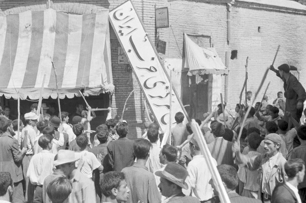 FILE - A crowd of demonstrators tear down the Iran Party's sign from the front of the headquarters in Tehran on Aug. 19, 1953, during the coup that ousted Prime Minister Mohammad Mossadegh and his government. In August 1953, a CIA-backed coup toppled Iran's prime minister, cementing the rule of Shah Mohammad Reza Pahlavi for over 25 years before the 1979 Islamic Revolution. (AP Photo, File)