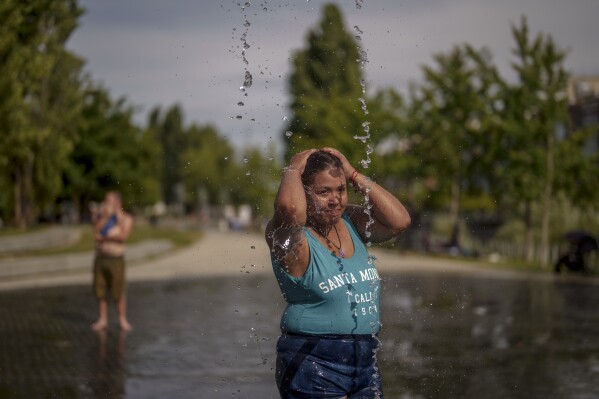 FILE - A woman cools off at an urban beach of Madrid Rio park in Madrid, Spain, July 12, 2023. At about summer's halfway point, the record-breaking heat and weather extremes are both unprecedented and unsurprising, hellish yet boring in some ways, scientists say. (AP Photo/Manu Fernandez, File)
