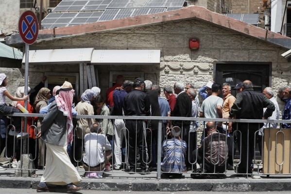 Syrians line up to retrieve money from an ATM in Damascus, Syria, Wednesday, May 14, 2025. (AP Photo/Omar Sanadiki)