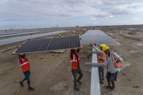 Workers install solar panels at the under-construction Adani Green Energy Limited's Renewable Energy Park in the salt desert of Karim Shahi village, near Khavda, Bhuj district near the India-Pakistan border in the western state of Gujarat, India, Thursday, Sept. 21, 2023. Nations have signed on to triple renewable energy by 2030. (AP Photo/Rafiq Maqbool)