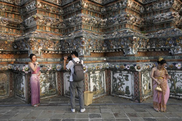 FILE - A Chinese tourist in traditional Thai dress poses for a photograp at Wat Arun or the "Temple of Dawn" in Bangkok, Thailand, on Jan. 12, 2023. On Thursday, Aug. 10, 2023, China increased the number of countries that its big-spending tourists can visit by more than 70 following the lifting of its last COVID-19 travel restrictions. (AP Photo/Sakchai Lalit, File)