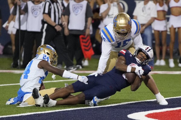 Arizona wide receiver Montana Lemonious-Craig (5) scores a touchdown against UCLA defensive back Jaylin Davies (24) and defensive lineman Laiatu Latu during the first half of an NCAA college football game Saturday, Nov. 4, 2023, in Tucson, Ariz. (AP Photo/Rick Scuteri)