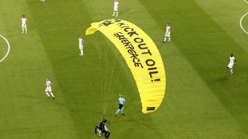 FILE - The German players look on as a Greenpeace paraglider lands in the stadium prior to the Euro 2020 soccer championship group F match between France and Germany at the Allianz Arena stadium in Munich, Tuesday, June 15, 2021. A German surgeon has been ordered to pay a fine of 7,200 euros ($7,900) for parachuting into the stadium before a European Championship match in Munich two years ago as part of a botched climate protest. (Alexander Hassenstein/AP Photo, Pool, File)