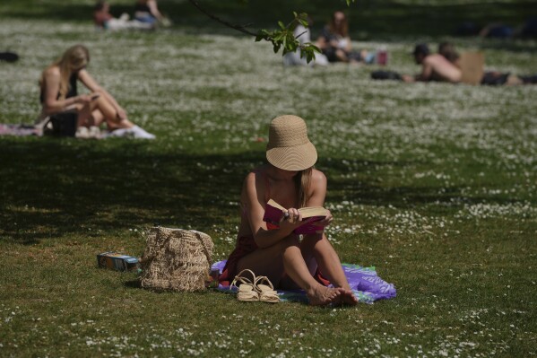 A woman reads on a sunny day at a park in London, Wednesday, April 30, 2025. (AP Photo/Kin Cheung)