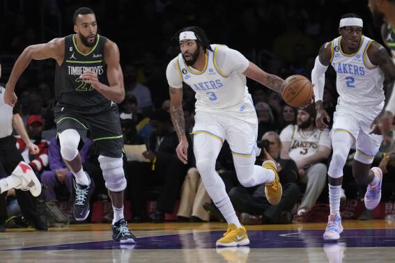 Los Angeles Lakers forward Anthony Davis (3) dribbles the ball past Minnesota Timberwolves center Rudy Gobert during the first half of an NBA basketball game Friday, March 3, 2023, in Los Angeles. (AP Photo/Marcio Jose Sanchez)