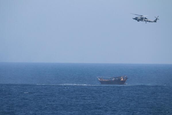 FILE - A U.S. Navy Seahawk helicopter flies over a stateless dhow later found to be carrying a hidden arms shipment in the Arabian Sea, May 6, 2021. The U.S. Navy's Mideast-based 5th Fleet will begin Tuesday, July 5, 2022, to offer rewards for information that could help sailors intercept weapons, drugs and other illicit shipments across the region. The program launches against the backdrop of tensions over Iran’s nuclear program and Tehran’s arming of Yemen’s Houthi rebels. (U.S. Navy via AP, File)