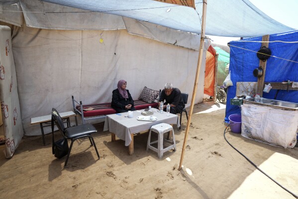 Ibrahim Abu Shaaban sits with his wife in their tent on Thursday, June 13, 2024, in Deir al-Balah in the Gaza Strip.  (AP Photo/Abdel Karim Hanna)