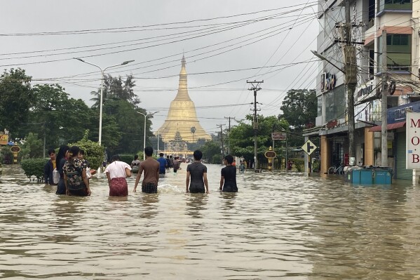 Local residents wade through a flooded road near Shwe Maw Taw pagoda in Bago, about 80 kilometers (50 miles) northeast of Yangon, Myanmar, Monday, Oct. 9, 2023. Flooding triggered by heavy monsoon rains in Myanmar’s southern areas has displaced more than 10,000 people and disrupted traffic on the rail lines that connect the country’s biggest cities, officials and state-run media said Monday. (AP Photo/Thein Zaw)
