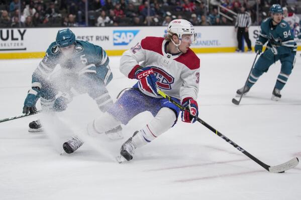 Montreal Canadiens center Rem Pitlick, center, moves the puck while defended by San Jose Sharks defenseman Matt Benning, left, during the second period of an NHL hockey game in San Jose, Calif., Tuesday, Feb. 28, 2023. (AP Photo/Godofredo A. Vásquez)