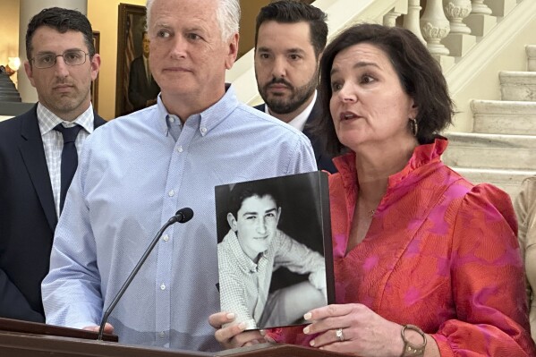 Dana Pope, with her husband John by her side, holds a photo of her son, Ethan, as she speaks at a news conference at the Georgia Capitol on May 2, 2024, after Gov. Brian Kemp signed a bill to regulate kratom. Extracted from the leaves of a tropical tree native to Southeast Asia, kratom is used to make capsules, powders and liquids. It's often sold in gas stations or smoke shops, marketed as an aid for pain, anxiety and drug dependence.The Popes say their son died after using kratom and that they hope the newly signed legislation will prevent other families from having to go through what they did. (AP Photo/Kate Brumback)
