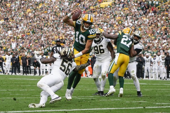 Jordan Love (10), quarterback de los Packers de Green Bay, esquiva una tackleada del linebacker de los Saints de Nueva Orleans, Demario Davis (56), en una jugada que terminó en acarreo de touchdown en la segunda mitad del juego de la NFL, el domingo 24 de septiembre de 2023, en Green Bay, Wisconsin. (AP Foto/Morry Gash)