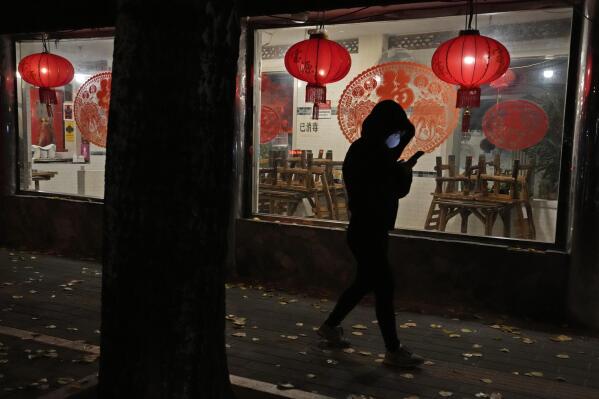 A woman wearing a mask walks past a restaurant closed to dine-in customers in Beijing, Tuesday, Nov. 22, 2022. More than 253,000 coronavirus cases have been found in China in the past three weeks and the daily average is rising, the government said Tuesday, adding to pressure on officials who are trying to reduce economic damage by easing controls that confine millions of people to their homes. (AP Photo/Ng Han Guan)