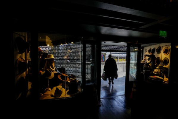 A customer walks out of the “Donde Golpea el Monito” hat shop and museum that preserves a hat-making tradition for more than a century, in Santiago, Chile, Saturday, April 5, 2025.(AP Photo/Esteban Felix)