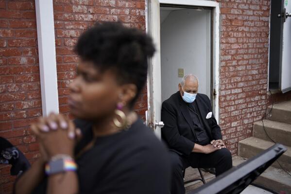 People pray during the dedication of a prayer wall at the historic Vernon African Methodist Episcopal Church in the Greenwood neighborhood during the centennial of the Tulsa Race Massacre, Monday, May 31, 2021, in Tulsa, Okla. The church was largely destroyed when a white mob descended on the prosperous Black neighborhood in 1921, burning, killing, looting and leveling a 35-square-block area. (AP Photo/John Locher)