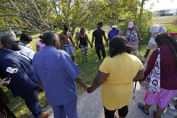 Residents gather for a prayer near the scene of a mass shooting at a Dollar General store, Saturday, Aug. 26, 2023, in Jacksonville, Fla. (AP Photo/John Raoux)