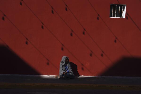 An Indigenous woman sits on a sidewalk in Izucar de Matamoros in the Mexican state of Puebla, Wednesday, June 29, 2022. (AP Photo/Marco Ugarte)