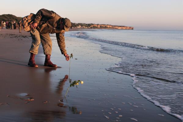 World War II reenactor put roses and flowers at dawn on Omaha Beach, in Saint-Laurent-sur-Mer, Normandy, France Monday, June 6, 2022, the day of 78th anniversary of the assault that helped bring an end to World War II. (AP Photo/Jeremias Gonzalez)
