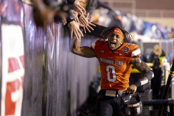 Oklahoma State running back Ollie Gordon II (0) celebrates with fans after the team's NCAA college football game against BYU on Saturday, Nov. 25, 2023, in Stillwater, Okla. (AP Photo/Mitch Alcala)