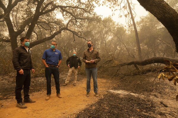 California Gov. Gavin Newsom, right, takes notes as he tours the North Complex Fire zone with California Secretary for Environmental Protection Jared Blumenfeld, left, and California Secretary for Natural Resources Wade Crowfoot, second left, in Butte County on Friday, Sept. 11, 2020, outside of Oroville, Calif. Newsom toured the fire-ravaged region Friday and strongly asserted that climate change was evident and pledged to redouble efforts to “decarbonize” the economy. (Paul Kitagaki Jr./The Sacramento Bee via AP, Pool)