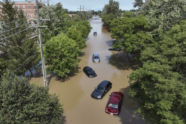 Cars sit stranded in floodwaters on Sheldon Road south of Ford road in Canton, Mich., Thursday, Aug. 24, 2023. Officials say parts of southeast Michigan got over 5 inches of rain by Thursday morning resulting in street flooding in the Detroit area, including tunnels leading to Detroit Metropolitan Airport. (David Guralnick/Detroit News via AP)
