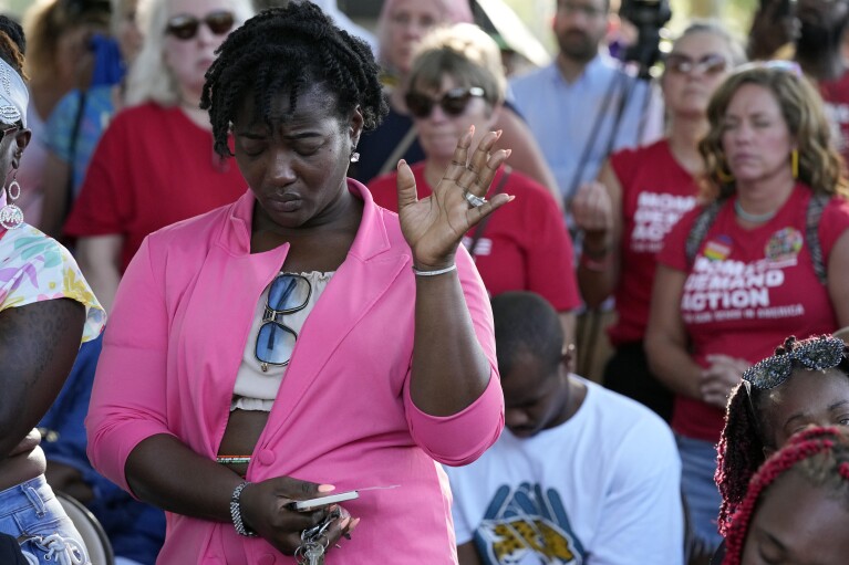 A woman attending a vigil for the victims of Saturday's mass shooting bows her head in prayer Sunday, Aug. 27, 2023, in Jacksonville, Fla. (AP Photo/John Raoux)