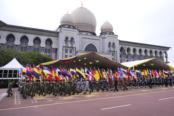 Military personnel carry states' flags as they march during the National Day parade in Putrajaya, Malaysia, Thursday, Aug. 31, 2023. Prime Minister Anwar Ibrahim urged Malaysians to unite and reject racial and religious bigotry, as the country marked its 66th year of freedom from British rule on Thursday with fireworks and a street parade. (AP Photo/Vincent Thian)