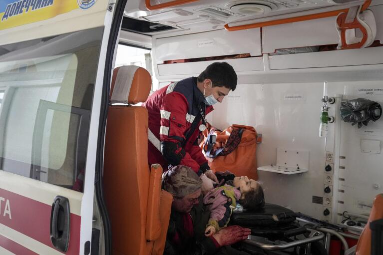 EDS NOTE: GRAPHIC CONTENT - Oleksandr Konovalov, an ambulance paramedic, performs CPR on a girl injured by shelling in a residential area as her dad sits, left, after arriving at the city hospital of Mariupol, eastern Ukraine, Sunday, Feb. 27, 2022. The girl did not survive. (AP Photo/Evgeniy Maloletka)
