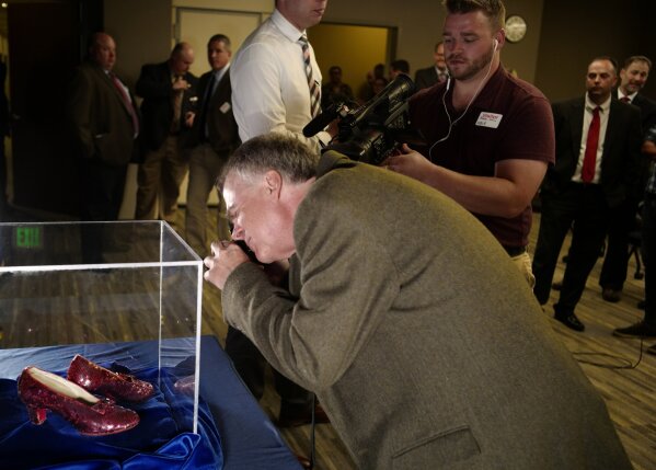 
              Rhys Thomas, the author of "the Ruby Slippers of Oz" took a closeup photo  of pair of ruby slippers once worn by actress Judy Garland in the "The Wizard of Oz" during a news conference Tuesday, Sept. 4, 2018, at the FBI office in Brooklyn Center, Minn. Authorities announced that the slippers, stolen in 2005 from the Judy Garland Museum in Grand Rapids, Minn., were recovered in a sting operation. The FBI says it has multiple suspects in the extortion and that the investigation continues. Four pairs of ruby slippers worn by Garland in the movie are known to exist. (Richard Tsong-Taatarii/Star Tribune via AP)
            
