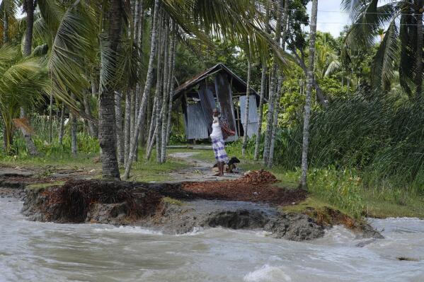 A man stands near an embankment eroded by the Meghna River in the Ramdaspur village in the Bhola district of Bangladesh on July 5, 2022. Mohammad Jewel and Arzu Begum were forced to flee the area last year when the river flooded and destroyed their home. (AP Photo/Mahmud Hossain Opu)