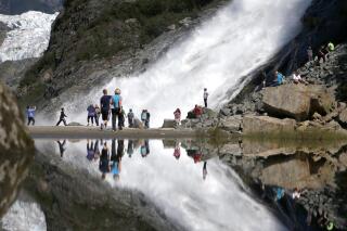 Tourists visiting the Mendenhall Glacier in the Tongass National Forest are reflected in a pool of water as they make their way to Nugget Falls in Juneau, Alaska, on July 31, 2013. The federal government plans to reinstate restrictions on road-building and logging on the country's largest national forest in southeast Alaska, the Tongass National Forest. (AP Photo/Charles Rex Arbogast, File)