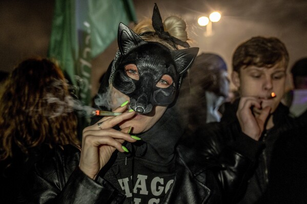 People smoke marijuana cigarette in front of the Brandenburg Gate during the 'Smoke-In' event in Berlin, Germany, Monday, April 1, 2024. Starting 1 April, Germany has legalised cannabis for personal use. As per the new law, Adults aged 18 and over will be allowed to carry up to 25 grams of cannabis for their own consumption. (AP Photo/Ebrahim Noroozi)