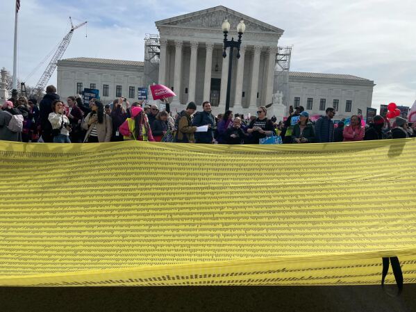 Abortion rights supporters unfurled a nearly-block long yellow banner in front of the court that represented a petition to protect medical abortion signed by 100,000 people.