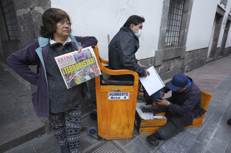 A newspaper vender holds a paper with the Spanish headline 