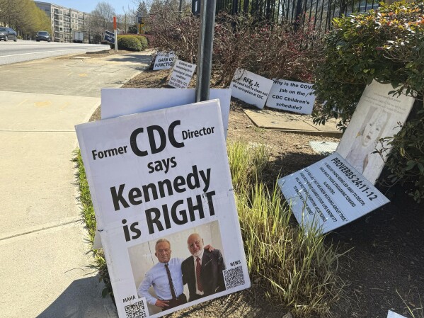 Signs placed by Mike Arnold, a supporter of Health Secretary Robert F. Kennedy Jr., are pictured as Arnold protests against the CDC outside the CDC campus in Atlanta, Thursday, March 27, 2025. (AP Photo/Kenya Hunter)