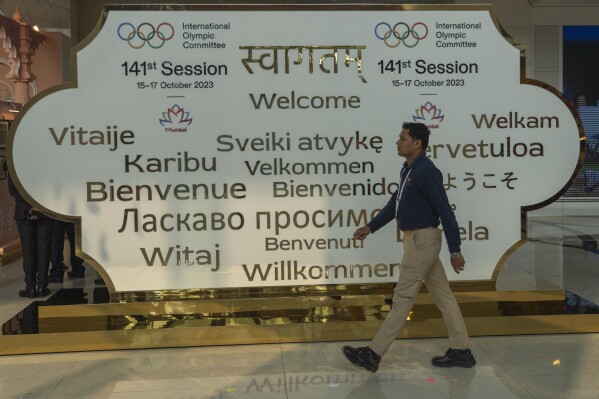 A man walks past a welcome sign at the entrance on the first day of the 141st International Olympic Committee (IOC) session in Mumbai, India, Sunday, Oct. 15, 2023. (AP Photo/Rafiq Maqbool)
