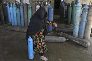 Una mujer carga un cilindro de oxígeno médico el sábado 19 de junio de 2021 en una planta privada en Kabul, Afganistán. (AP Foto/Rahmat Gul)