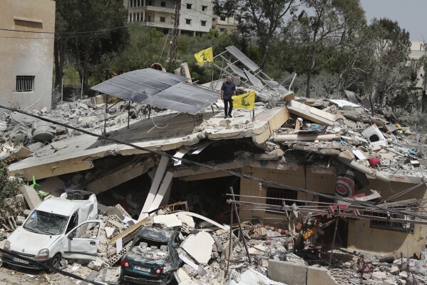 A man stands on a house that was destroyed by an Israeli airstrike, in Hanine village, south Lebanon, Thursday, April 25, 2024. Hezbollah militants and Israeli forces have been exchanging fire since a day after the Israel-Hamas war began on Oct. 7. (AP Photo/Mohammed Zaatari)