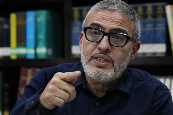 FILE - Doctor Ghassan Abu Sitta, a Palestinian-British plastic surgeon specializing in conflict medicine, speaks during an interview with The Associated Press at the Institute for Palestine Studies in Beirut, Lebanon, Saturday, Dec. 9, 2023. A prominent British-Palestinian surgeon who volunteered in Gaza hospitals during the first weeks of the Israel-Hamas war said he was denied entry to Germany Friday to take part in a pro-Palestinian conference — an event that police later ended early. Dr. Ghassan Abu Sitta said he arrived at Berlin airport on Friday morning before being stopped at passport control, where he was held for several hours and then told he had to return to the U.K. (AP Photo/Hussein Malla, File)