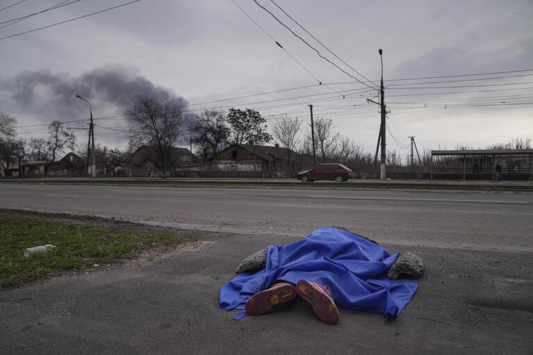 A body lies covered by a tarp in the street in Mariupol, Ukraine, Monday, March 7, 2022. (AP Photo/Evgeniy Maloletka)
