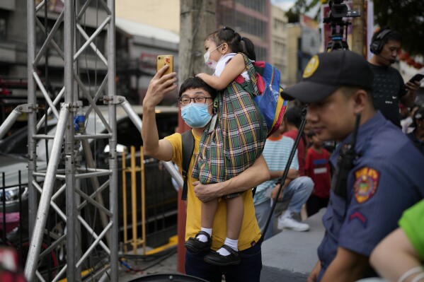 A man carries her daughter as they watch celebrations for the 430th anniversary of Manila's Chinatown, said to be the oldest in the world, at the capital's Binondo district, Philippines on Thursday, Feb. 1, 2024. Crowds are flocking to Manila's Chinatown to usher in the Year of the Wood Dragon and experience lively traditional dances on lantern-lit streets with food, lucky charms and prayers for good fortune. (APPhoto/Aaron Favila)