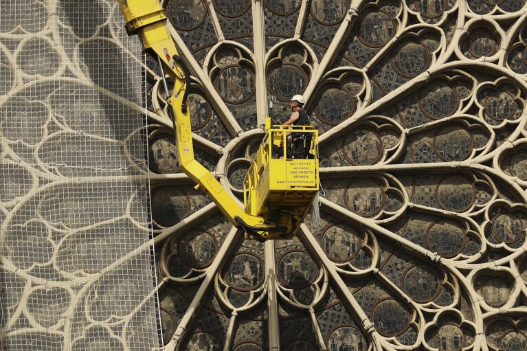 FILE - Workers fix a net to cover one of the iconic stained glass windows of the Notre Dame Cathedral in Paris, Sunday, April 21, 2019. The restoration of Notre Dame hits a milestone Friday, Dec. 8, 2023: one year until the cathedral reopens its huge doors to the public. (AP Photo/Francisco Seco, File)