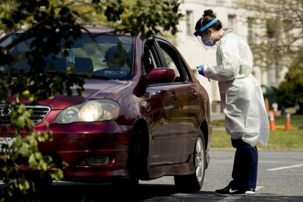A medical worker prepares to test a young man for COVID-19 at a Children's National Hospital drive-through (drive-in) coronavirus testing site at Trinity University, Thursday, April 16, 2020, in Washington. (AP Photo/Andrew Harnik)