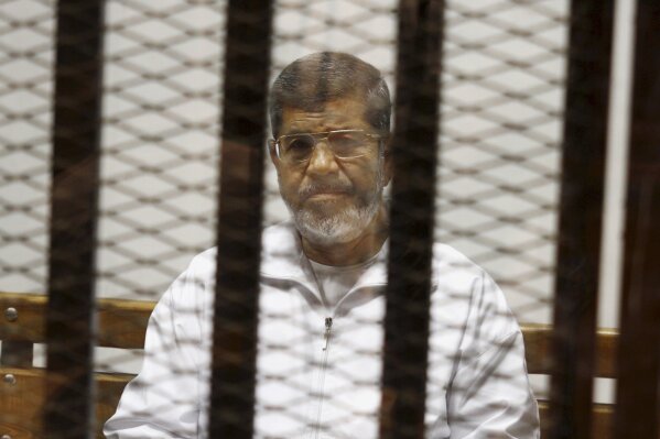 FILE - In this May 8, 2014 file photo, Egypt's ousted Islamist President Mohammed Morsi sits in a defendant cage in the Police Academy courthouse in Cairo, Egypt.  Morsi’s collapse and death in a Cairo courtroom on June 17, 2019,  was a brief rallying point for the Muslim Brotherhood whose influence waned dramatically in the Middle East since the 2013 military coup in Egypt which had widespread public support at the time. The long-running enmity between the Brotherhood and most Sunni-led governments highlights the deep divisions among Sunni Muslims. It adds a further complication to the volatile region, where the split between Sunnis and Shiite Muslims has created rival camps.  (AP Photo/Tarek el-Gabbas, File)
