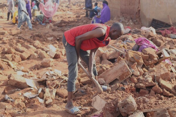 A man searches the rubble in a flooded area after heavy rainfall in the market town of Mokwa, north-central Nigeria, Saturday May 31, 2025. (AP Photo/Usman Salihu Mokwa)